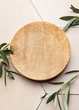 Yuvarlak ahşap tabaklar ve zeytin dalları minimalist, kırsal bir masa başı ortamı oluşturuyor.