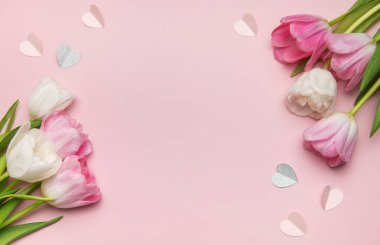 Güzel bahar laleleri ve kağıt kalpler pembe bir zemin üzerinde güzel bir sınır oluşturuyor, romantik durumlar için mükemmel.