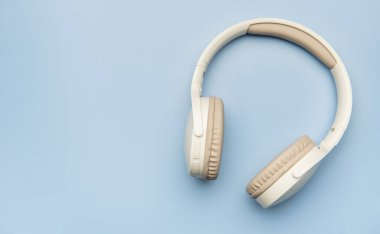 Kablosuz kulaklıklar canlı mavi bir arka planda dinleniyor, müzik severler için minimalist bir estetiği somutlaştırıyor.