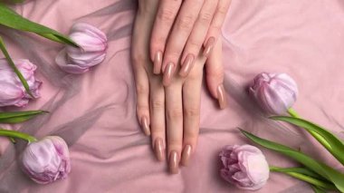 Mor lalelerin yanında nişan yüzüğüyle yeni manikürünü gösteren bir kadın.