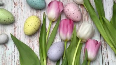 Renkli paskalya yumurtaları ve laleler kırsal ahşap bir masa üzerinde güzel bir bahar düzenlemesi oluşturur.
