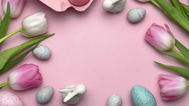 Pembe laleli Paskalya süslemeleri, renkli yumurtalar ve pembe arka planda neşeli bir çerçeve oluşturan tavşan heykelcikleri.