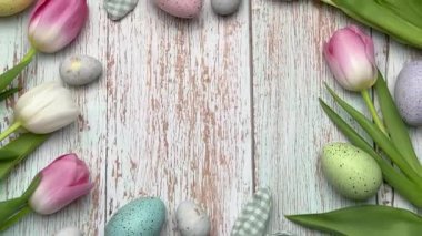 Paskalya yumurtaları ve laleler kırsal beyaz ahşap arka planda renkli bir çerçeve oluşturuyor.