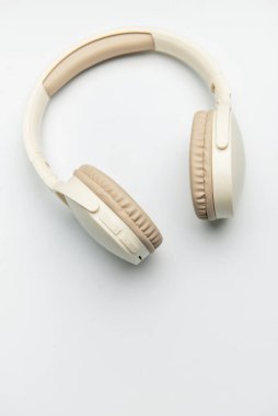 Beyaz arka planda izole edilmiş bej ve beyaz kablosuz kulaklıklar, müzik dinlemeyi, podcast zevkini veya ses iletişimini temsil ediyor
