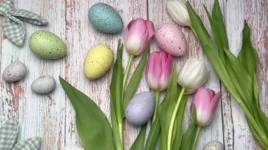 Renkli paskalya yumurtaları ve laleler kırsal ahşap bir masa üzerinde güzel bir bahar düzenlemesi oluşturur.