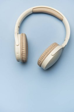 Kablosuz kulaklıklar canlı mavi bir arka planda dinleniyor, müzik severler için minimalist bir estetiği somutlaştırıyor.