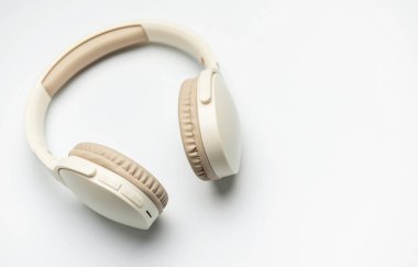 Beyaz arka planda izole edilmiş bej ve beyaz kablosuz kulaklıklar, müzik dinlemeyi, podcast zevkini veya ses iletişimini temsil ediyor