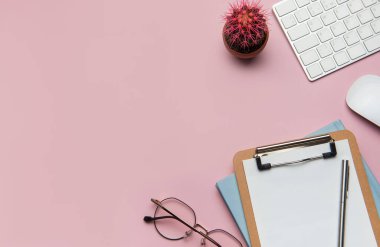 Üzerinde klavye, fare, dosya, gözlük ve kaktüs olan ofis masası.