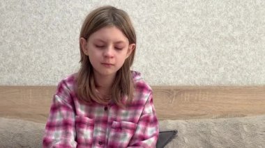 Genç kız yatakta oturuyor ve ağlamaya başlıyor.