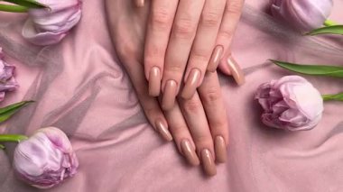 Mor lalelerin yanında nişan yüzüğüyle yeni manikürünü gösteren bir kadın.