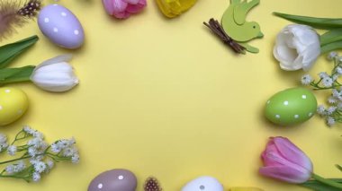 Paskalya yumurtaları ve laleler pastel yeşil bir yüzey üzerinde güzel bir bahar düzenlemesi oluşturur.