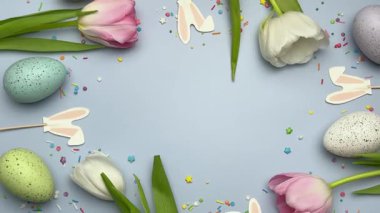 Paskalya yumurtaları ve laleler pastel yeşil bir yüzey üzerinde güzel bir bahar düzenlemesi oluşturur.