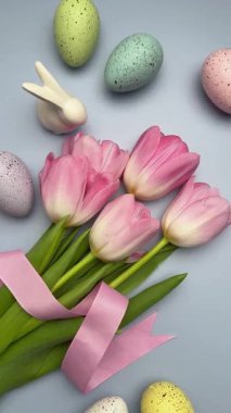 Paskalya yumurtaları ve laleler pastel yeşil bir yüzey üzerinde güzel bir bahar düzenlemesi oluşturur.