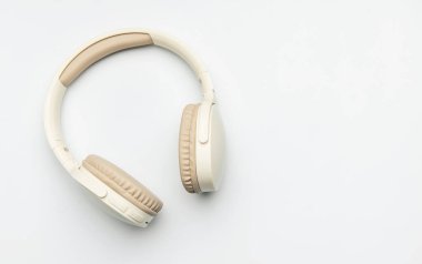Beyaz arka planda izole edilmiş bej ve beyaz kablosuz kulaklıklar, müzik dinlemeyi, podcast zevkini veya ses iletişimini temsil ediyor