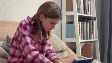 Hüsrana uğramış genç bir kız yatakta otururken tabletinde sorun yaşıyor.