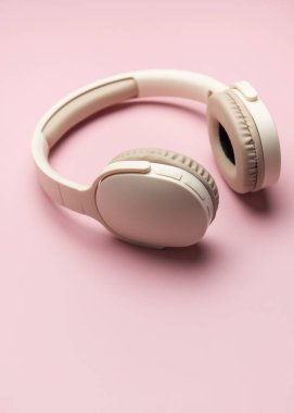 Müzik, teknoloji ve kişisel ses zevkini temsil eden canlı pembe bir fon üzerinde dinlenen şık kulaklıklar.