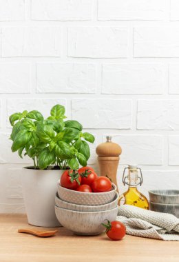 Taze fesleğen, zeytinyağı, biber değirmeni ve mutfak havlusu dolu taze bir mutfak sahnesi yaratıyor.