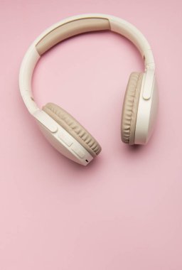 Müzik, teknoloji ve kişisel ses zevkini temsil eden canlı pembe bir fon üzerinde dinlenen şık kulaklıklar.