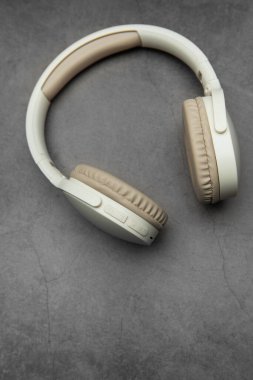 Modern kablosuz kulaklıklar gri bir yüzeyde, müzik dinlemeyi, podcast zevkini veya ses iletişimini temsil ediyor.