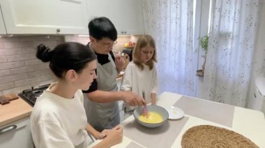 Büyükannem torunlarına mutfakta yumurta çırpmayı öğretiyor.