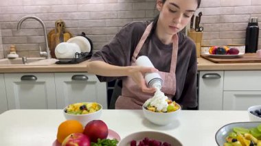 Modern mutfakta şef meyve salatasını krem şanti ve ahududu ile süslüyor. Sağlıklı ve lezzetli tatlı hazırlığı.