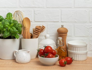 Modern mutfak tezgahında taze malzemeler, ahşap çatal bıçaklar ve beyaz seramik sofra takımı sergilenerek şık ve davetkar bir mutfak ortamı oluşturulur.