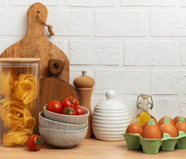 Mutfak tezgahında makarna, domates, yumurta ve zeytinyağı gibi lezzetli İtalyan yemekleri sergilenerek sıcak ve davetkar bir atmosfer yaratılıyor.