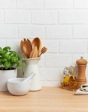 Tahta kaşıklar, çırpı, bal kabuğu, harç ve tokmak, yağ, baharat ve fesleğen bitkisi rahat bir mutfak ortamı yaratıyor.