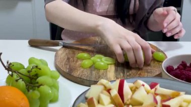 Şef üzüm, elma, portakal, ahududu ve yaban mersinli meyve salatası hazırlıyor.