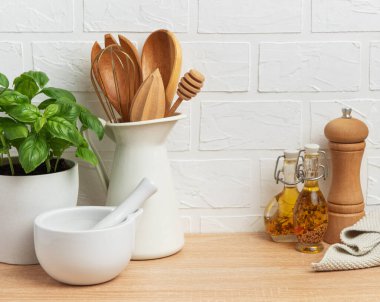 Tahta kaşıklar, çırpı, bal kabuğu, harç ve tokmak, yağ, baharat ve fesleğen bitkisi rahat bir mutfak ortamı yaratıyor.
