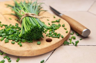 Taze soğan demeti ve ahşap tahtada doğranmış soğan, pişirmeye hazır.