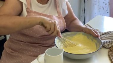 Baker bir tarifi takip eder, kasedeki diğer malzemelere süt ekler ve onları birlikte çırpar.