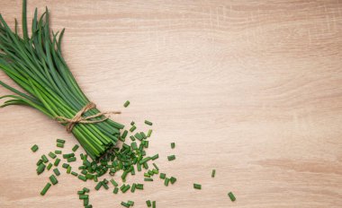 Ahşap bir masaya saçılmış sicimle bağlanmış, aşçılık için hazır taze kesilmiş soğanlar.