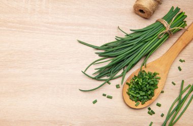 Taze soğan demeti ve ahşap kaşık ve masada doğranmış soğan.