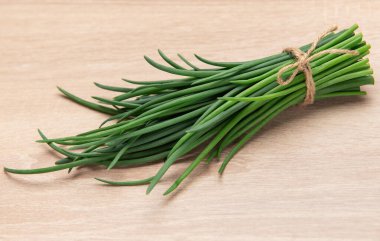 Tahta bir yüzeye bağlanmış bir demet yeşil soğan.