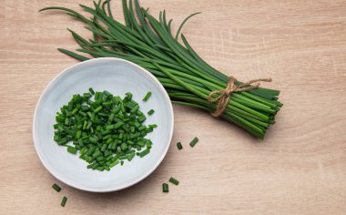 Taze soğanlar paketlenmiş ve ahşap bir yüzey üzerinde bir kasede doğranmış.