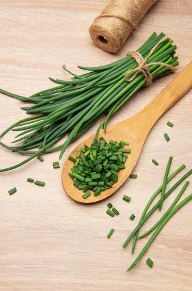 Taze soğan demeti ve ahşap kaşık ve masada doğranmış soğan.