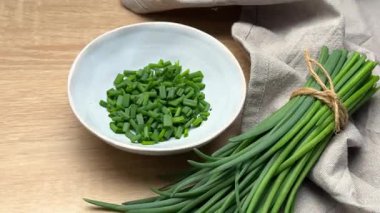 Taze soğanlar ahşap bir masada doğranır.