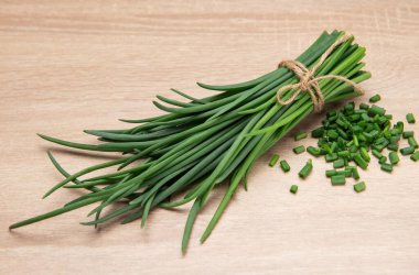 Tahta bir masada doğranmış soğan ve sicimle bağlanmış taze soğanlar.