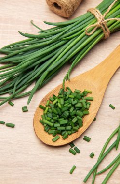 Taze soğan demeti ve ahşap kaşık ve masada doğranmış soğan.