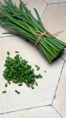 Taze kesilmiş soğanlar sicimle bağlanmış, fayanslı bir yüzeyde dinleniyor.