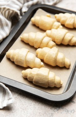 Fırınlanmamış kruvasanlar parşömen kağıdıyla kaplanmış, fırın için hazır.