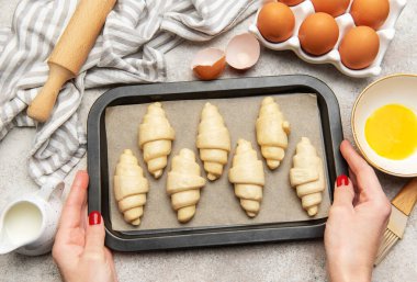 Fırıncı pişmeye hazır pişmemiş kruvasan hazırlıyor.