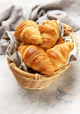 Taze pişmiş kruvasanlar kırsal bir masada hasır sepetin içinde dinleniyor.