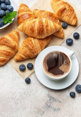 Taze pişmiş kruvasan, yabanmersini ve lezzetli bir kahvaltı hazırlayan dumanı tüten kahve.