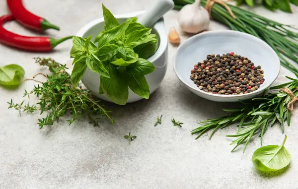 Aromatik otlar, baharatlar ve dokulu bir yüzeye dizilmiş renkli kırmızı biberler aşçılık ürünlerini geliştirmeye hazırdır.