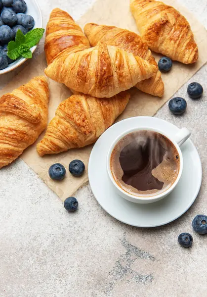 Taze pişmiş kruvasan, yabanmersini ve lezzetli bir kahvaltı hazırlayan dumanı tüten kahve.