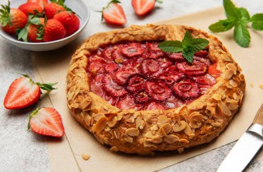 Badem gevreği ve nane yapraklarıyla süslenmiş taze pişmiş çilek galeti.