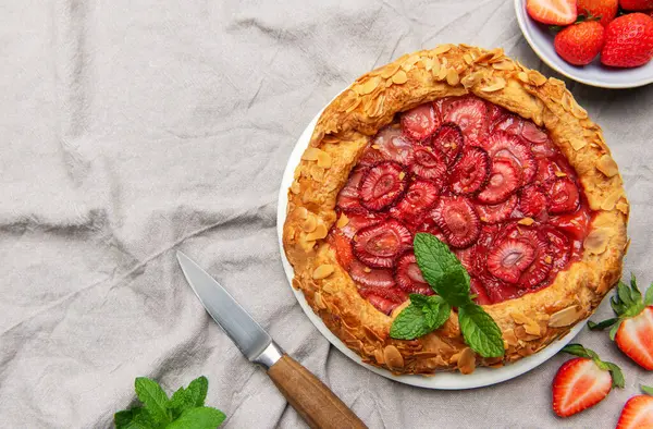 Badem gevreği ve nane yapraklı taze fırınlanmış çilek galeti taze çilek ve sütle servis edilir. Yaz tatlısı için mükemmel.