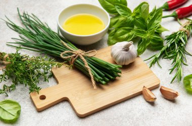 Taze soğanlar, baharatlar, sarımsak, kırmızı biber ve zeytinyağı ahşap kesme tahtasına dizilir, pişirmeye hazır.